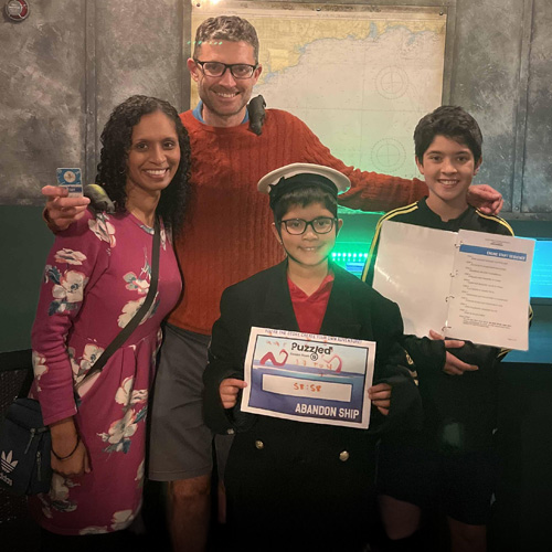 A family having their photo taken after playing at Puzzled Escape Rooms